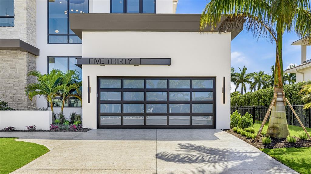 A modern home exterior features a glass-paneled garage door with a "FIVE THIRTY" sign above — 530 CHIPPING LANE, LONGBOAT KEY, FL