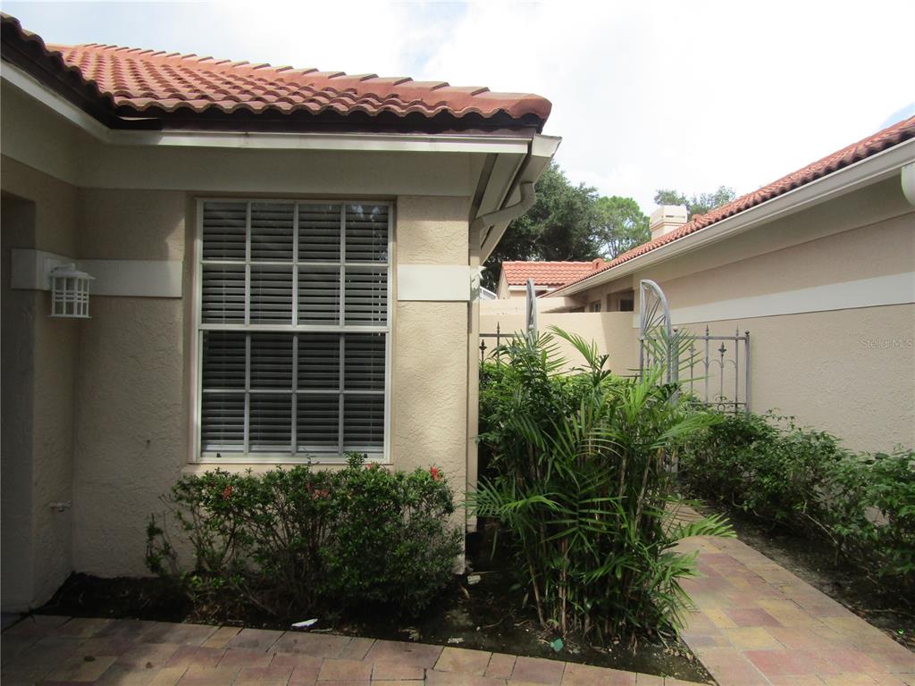 A view of a house exterior with a paved walkway, a window, and a metal gate — 4026 LYNDHURST COURT UNIT 13, SARASOTA, FL