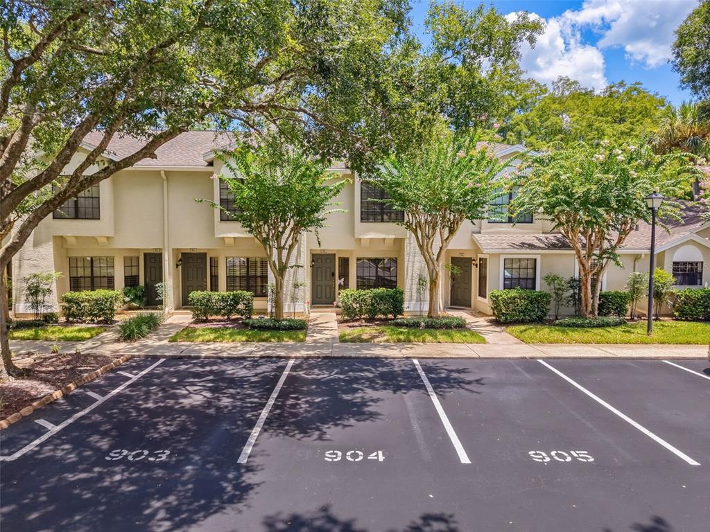 A multi-unit residential building with beige siding faces a parking lot with numbered spaces — 5100 BURCHETTE ROAD UNIT 905, TAMPA, FL