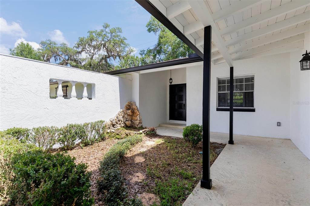 A white exterior home features a covered porch, a black front door, and a stone feature — 515 TIVOLI COURT, ALTAMONTE SPRINGS, FL