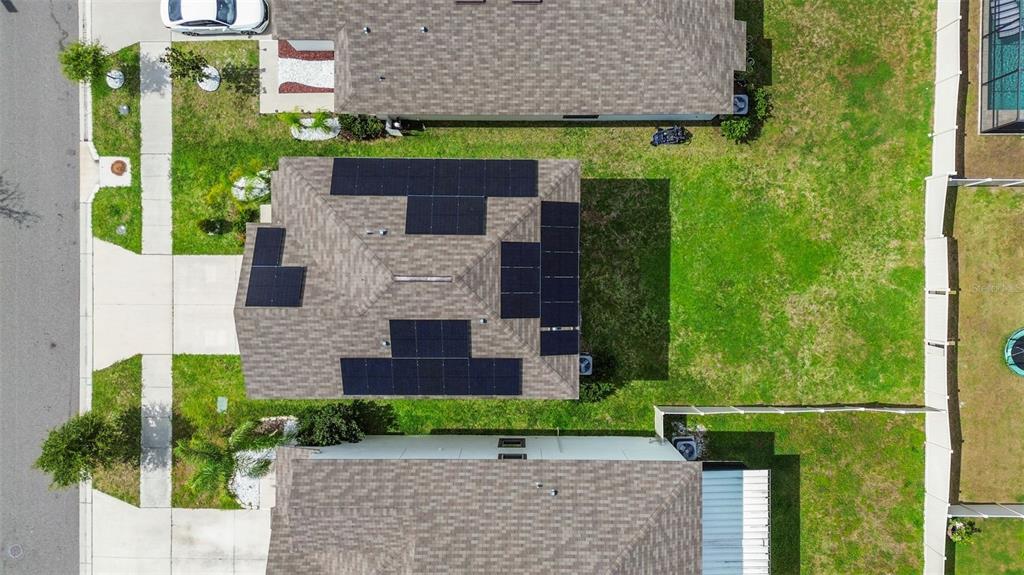 An aerial view shows a residential house with solar panels installed on its shingled roof — 16671 KINGMAN REEF STREET, WIMAUMA, FL