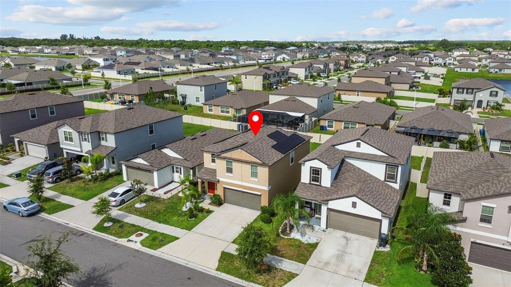 An aerial view shows a two-story suburban house with solar panels on the roof — 16671 KINGMAN REEF STREET, WIMAUMA, FL