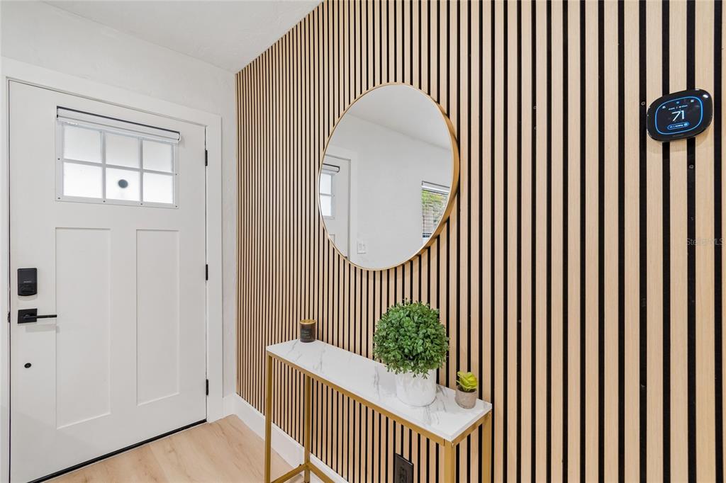 An entryway features a white door, a marble-topped console table, and a slatted wood wall — 4730 W BAY VISTA AVENUE, TAMPA, FL