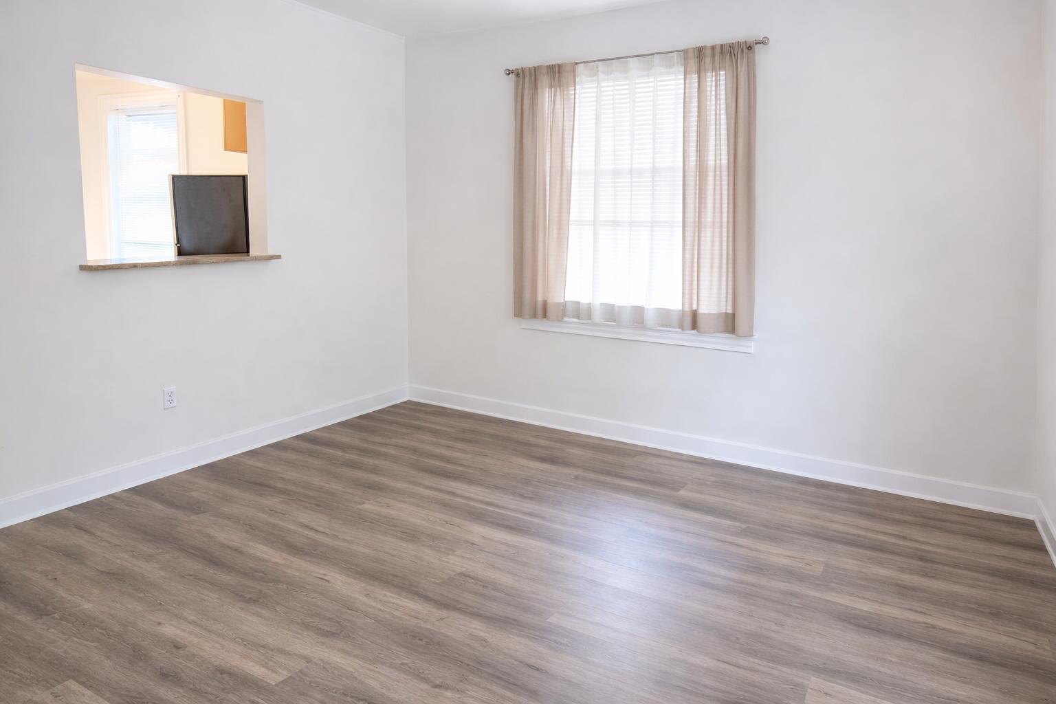 An empty room with white walls, wood-look flooring, a window with curtains, and a pass-through opening — 333 Walton Boulevard # 3, West Palm Beach FL 33405, WEST PALM BEACH, FL