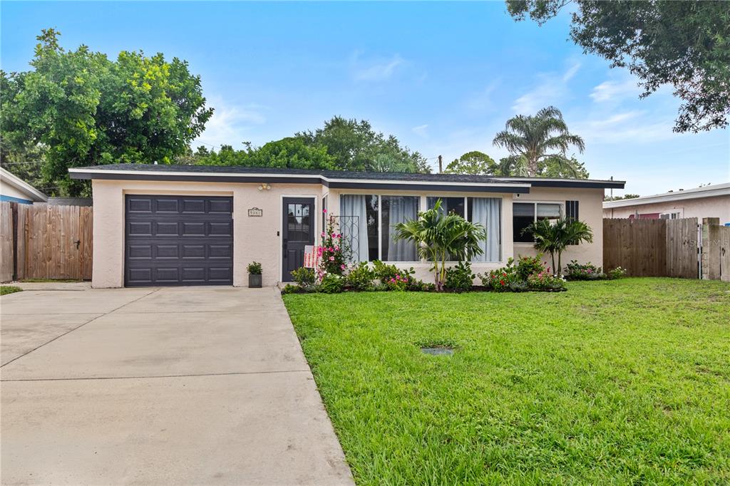A single-story house with a garage, concrete driveway, and front yard landscaping under a blue sky — 5841 67TH AVENUE N, PINELLAS PARK, FL