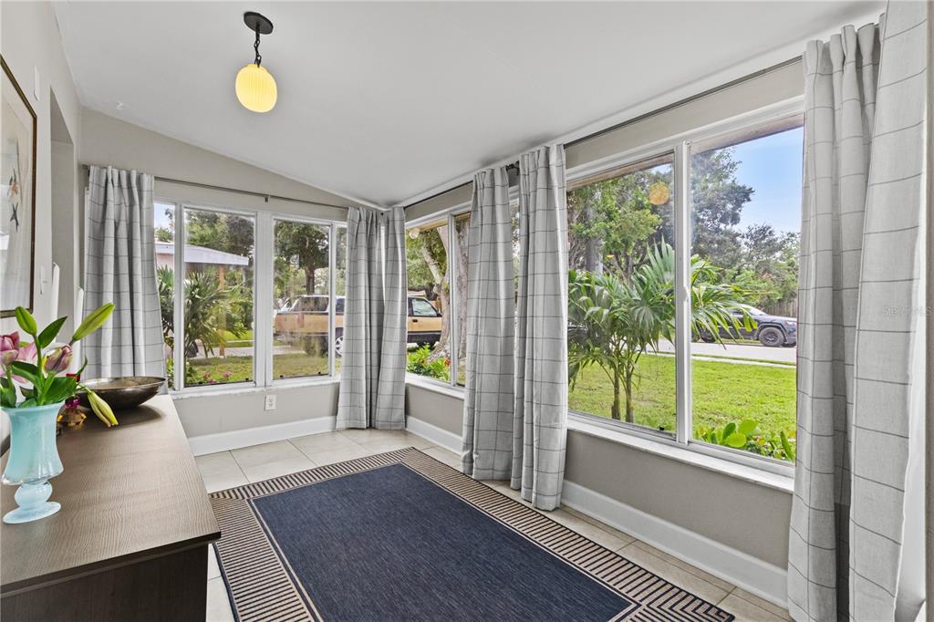 A sunroom with tile floors, large windows, plaid curtains, and a dark blue area rug — 5841 67TH AVENUE N, PINELLAS PARK, FL