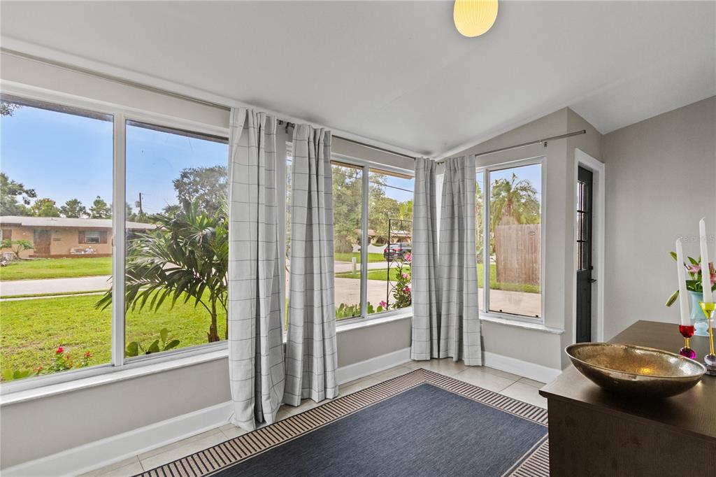 A sunroom with large windows, light gray walls, tile flooring, and a dark area rug — 5841 67TH AVENUE N, PINELLAS PARK, FL