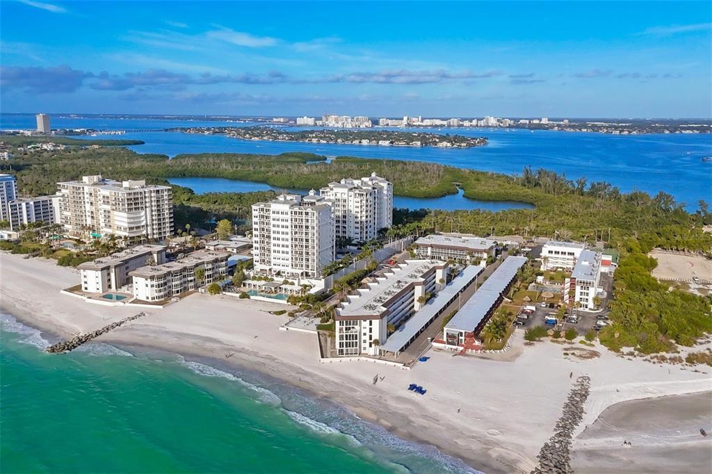 An aerial view of a beachfront resort complex with multiple buildings, pools, and sandy beaches — 2110 BENJAMIN FRANKLIN DRIVE UNIT 104, SARASOTA, FL
