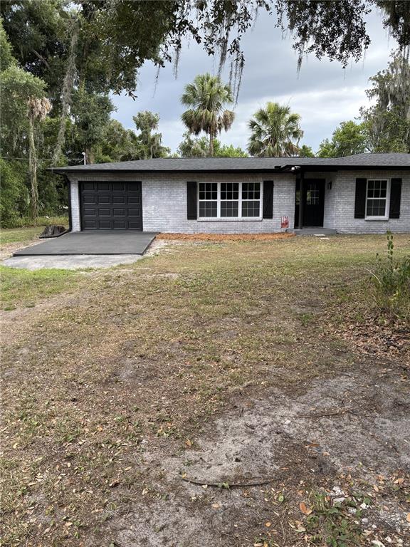 A single-story house with a gray brick exterior, black shutters, and a dark garage door — 2911 WILLIAMS ROAD, PLANT CITY, FL