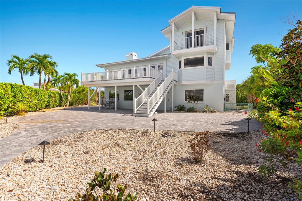 A light blue multi-story house features a large elevated deck with stairs and paver patio — 13065 VIA AURELIA, PLACIDA, FL