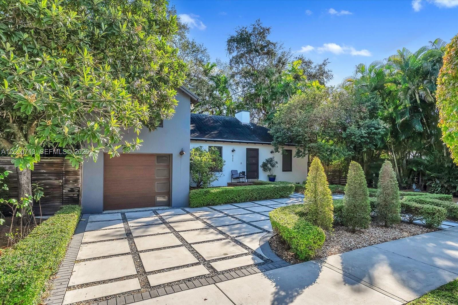 A single-story house with a wooden garage door and a paved driveway with grass joints — 8225 NE 8th Ct, Miami FL 33138, MIAMI, FL