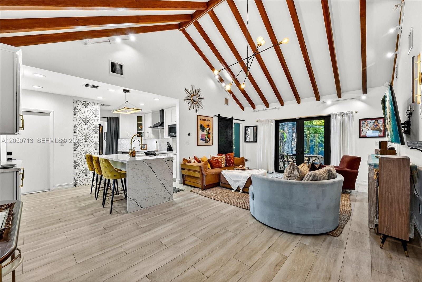 An open-concept living room and kitchen feature vaulted ceilings with exposed wood beams — 8225 NE 8th Ct, Miami FL 33138, MIAMI, FL