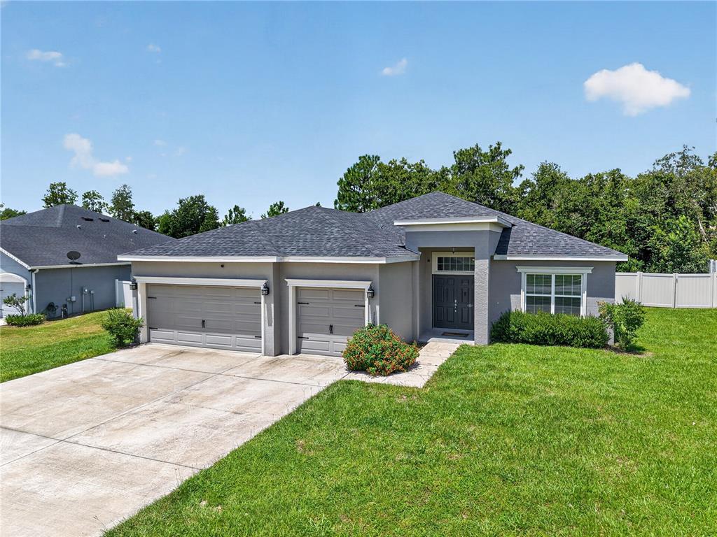 A single-story house with a gray exterior, a two-car garage, and a concrete driveway — 11370 SW 57TH AVENUE, OCALA, FL