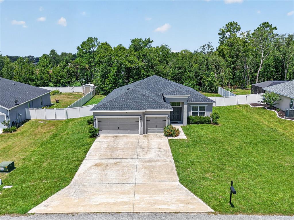 An aerial view of a single-story suburban house with a three-car garage and driveway — 11370 SW 57TH AVENUE, OCALA, FL