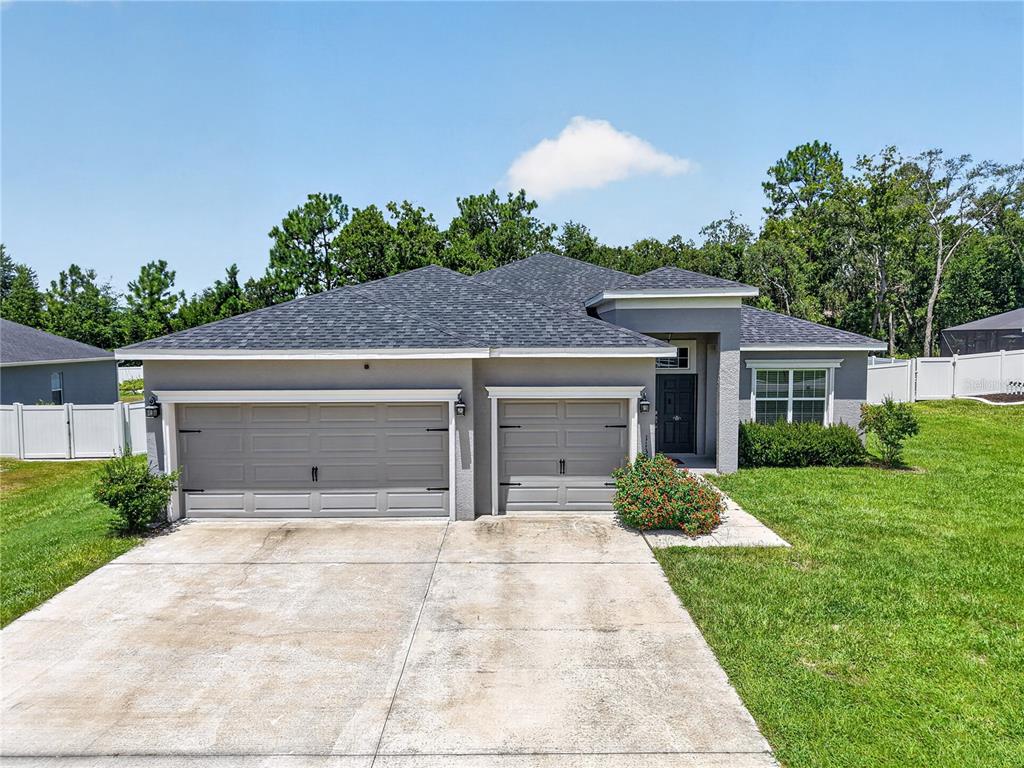 A single-story house with a gray exterior, a three-car garage, and a concrete driveway — 11370 SW 57TH AVENUE, OCALA, FL