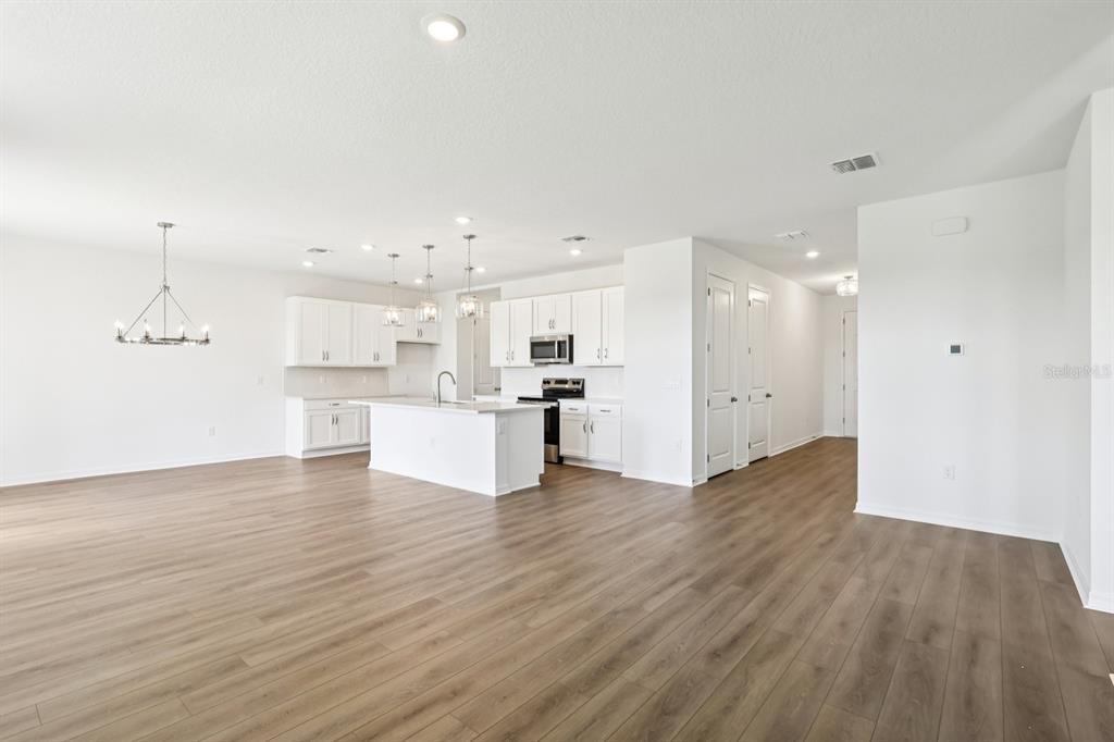 A bright, open-concept kitchen features white cabinetry, a center island, and wood-look flooring — 1634 CANE BAMBOO DRIVE, ST CLOUD, FL
