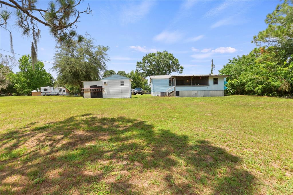 A light blue mobile home and a small white shed sit on a grassy lot — 5360 DILLMAN LANE, POLK CITY, FL