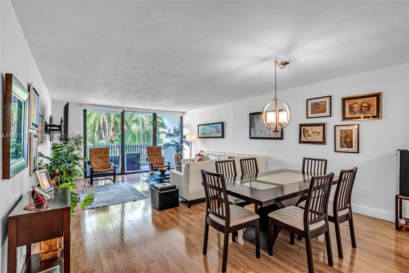 A living and dining area features hardwood floors, a balcony, and a modern light fixture — 100 Ocean Lane Dr # 301, Key Biscayne FL 33149, KEY BISCAYNE, FL