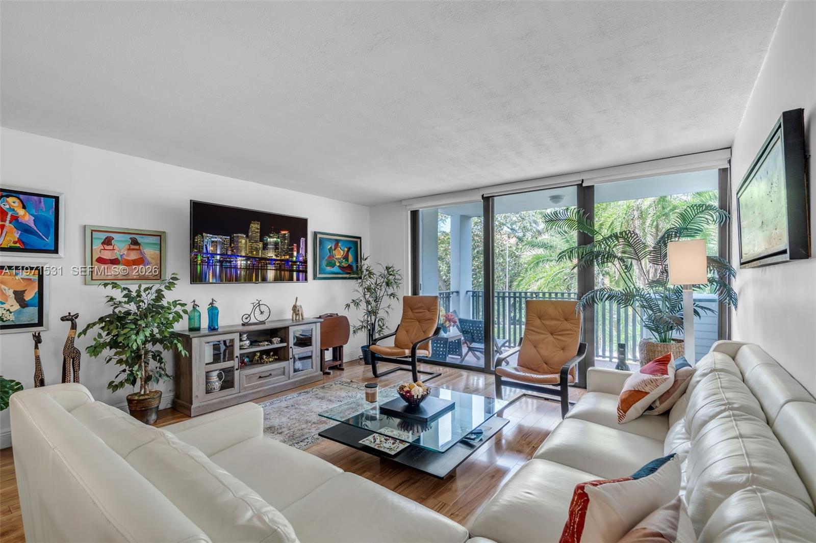 A bright living room features white leather sofas, a glass coffee table, and a balcony — 100 Ocean Lane Dr # 301, Key Biscayne FL 33149, KEY BISCAYNE, FL