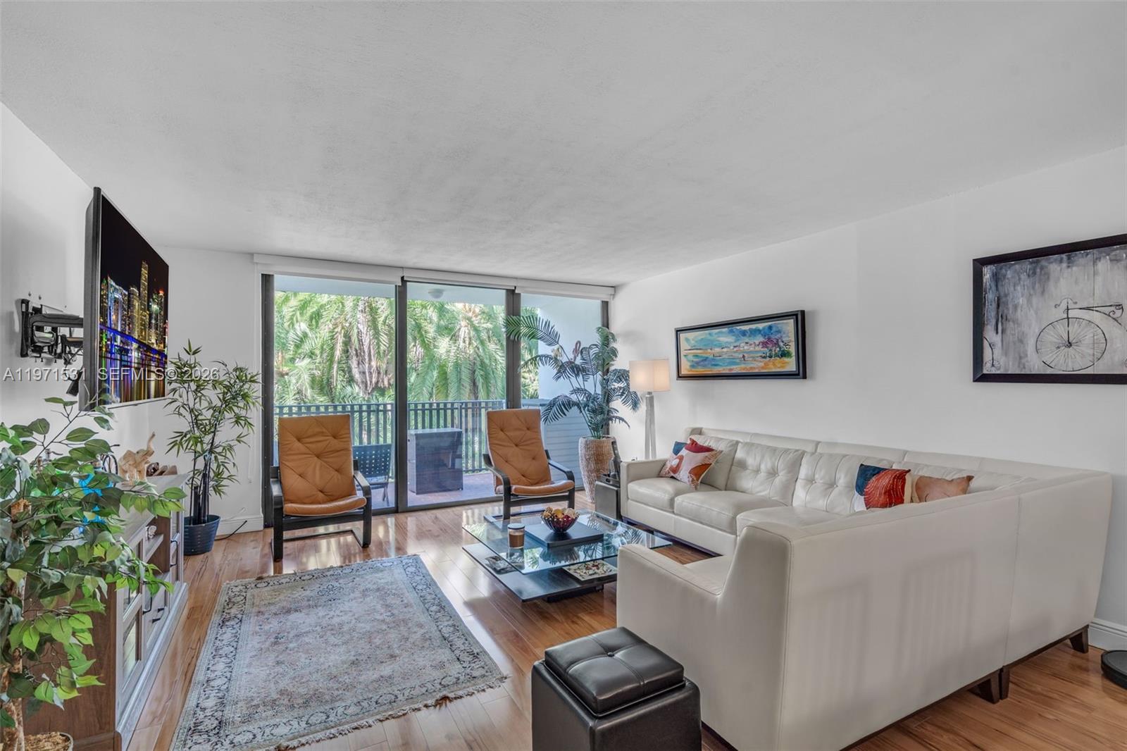 A living room features a white sofa, two leather chairs, a glass coffee table, and balcony — 100 Ocean Lane Dr # 301, Key Biscayne FL 33149, KEY BISCAYNE, FL