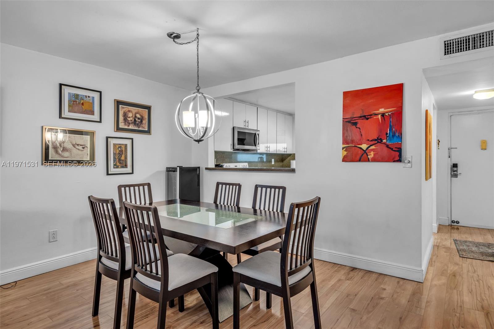 A dining room features a dark wood table, six chairs, and a pass-through kitchen window — 100 Ocean Lane Dr # 301, Key Biscayne FL 33149, KEY BISCAYNE, FL