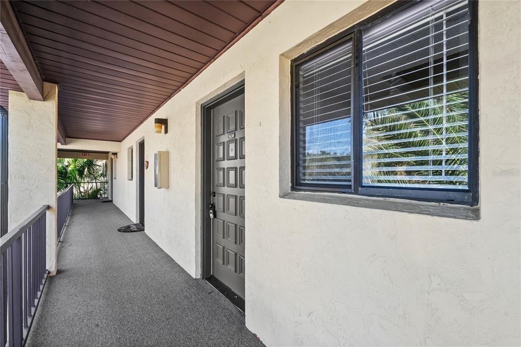 An exterior walkway leads to a gray apartment door numbered 608 with a nearby window — 3700 BENEVA ROAD UNIT 0, SARASOTA, FL