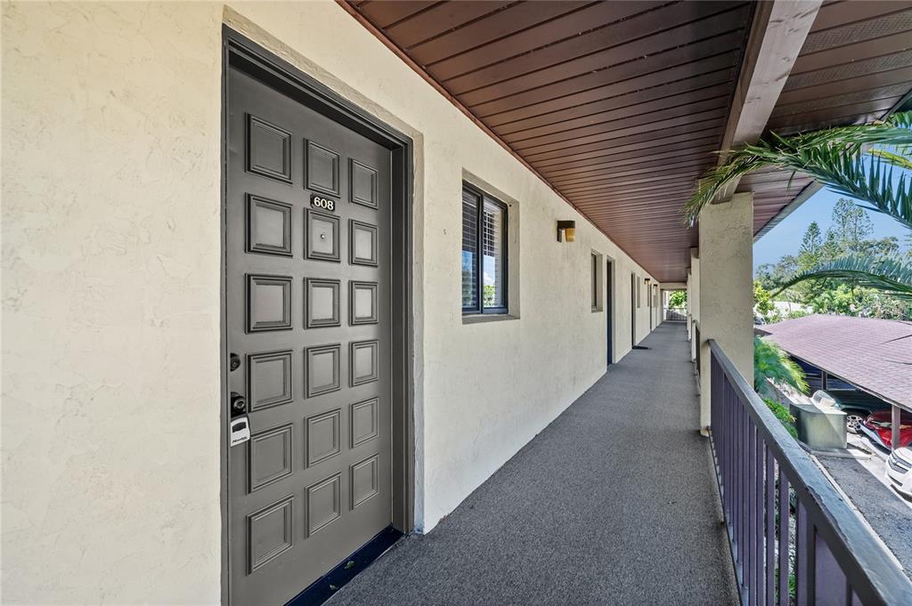 An exterior view of an apartment building hallway with a gray door numbered 608 — 3700 BENEVA ROAD UNIT 0, SARASOTA, FL
