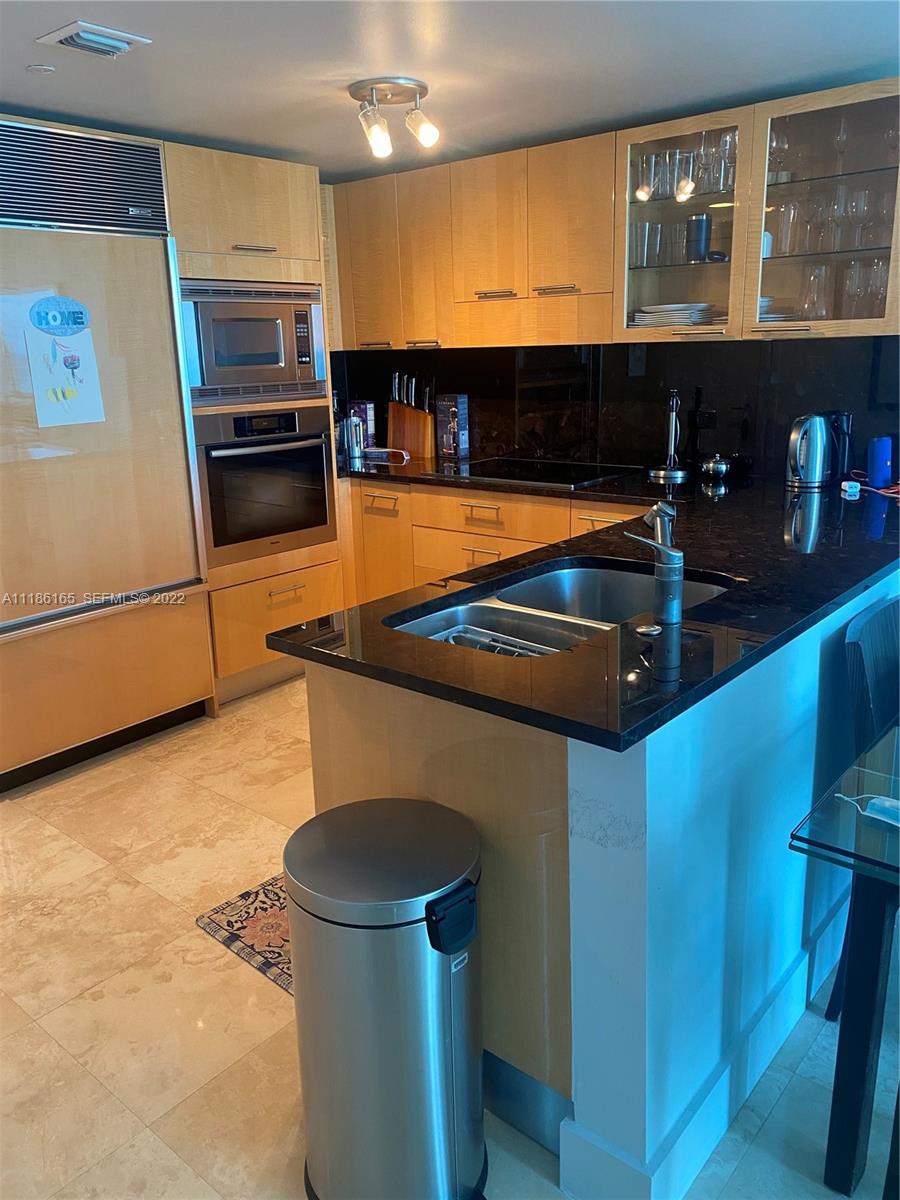 A kitchen features light wood cabinets, black granite countertops, stainless steel appliances, and tile flooring — 6801 Collins Ave, Miami Beach FL 33141, MIAMI BEACH, FL