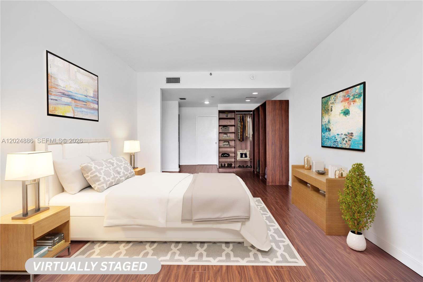 This is a virtually staged bedroom featuring a bed, wooden flooring, and open closet shelving — 151 Crandon Blvd # 441, Key Biscayne FL 33149, KEY BISCAYNE, FL