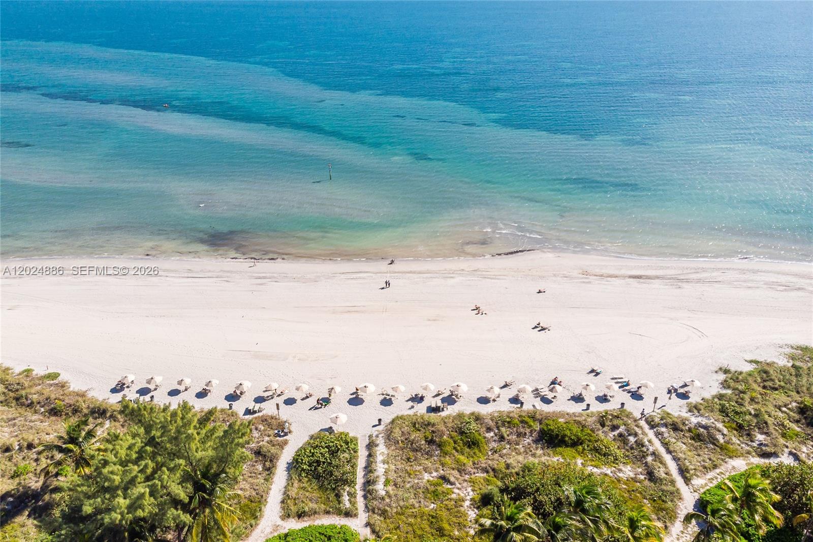 An aerial view shows a sandy beach with umbrellas and vegetation along the shoreline — 151 Crandon Blvd # 441, Key Biscayne FL 33149, KEY BISCAYNE, FL