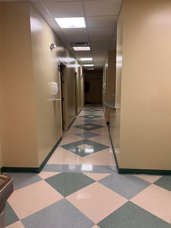 A long hallway features tan walls, a green and beige checkered floor, and recessed lighting — 5999 DUNDEE ROAD UNIT 800, WINTER HAVEN, FL
