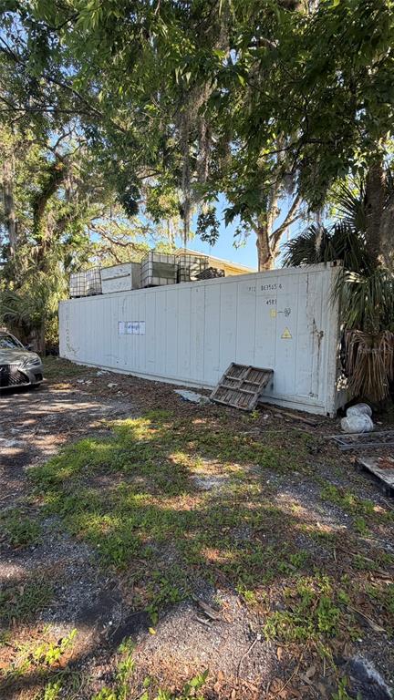 A white shipping container sits on a gravel lot beneath large, moss-draped trees — 6601 RIVERSIDE DRIVE, YANKEETOWN, FL