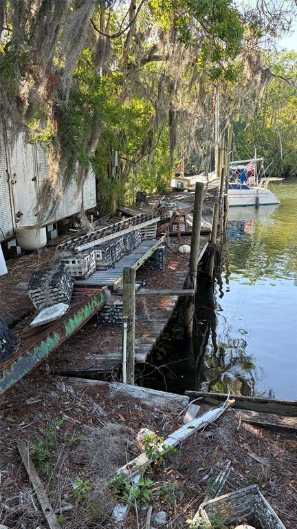 A weathered wooden dock sits along a riverbank with stacked crates and a nearby boat — 6601 RIVERSIDE DRIVE, YANKEETOWN, FL