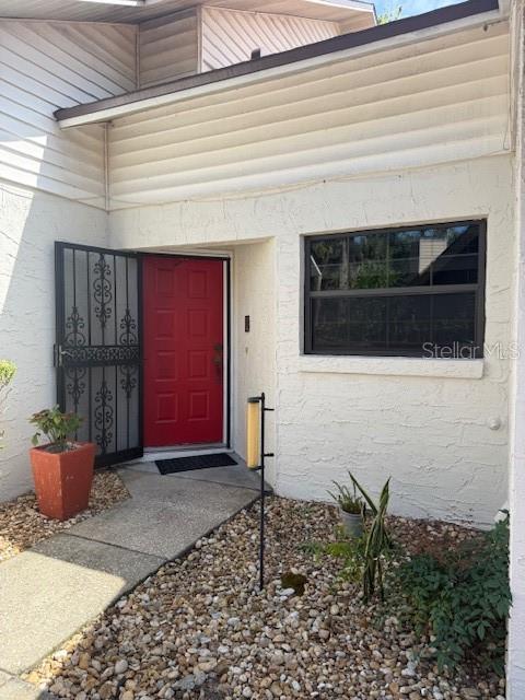 The exterior of a home features a red front door, a screen door, and a window — 823 LONG MEADOW COURT, PORT ORANGE, FL