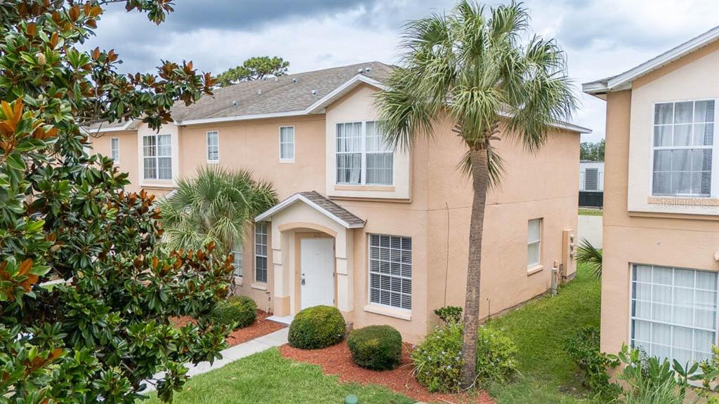 A two-story tan stucco townhouse with a palm tree and a small front entryway — 678 CAPTIVA CIRCLE, KISSIMMEE, FL