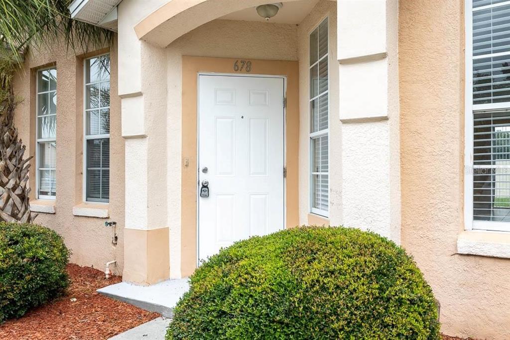 The exterior of a house features a white front door with the number 678 above — 678 CAPTIVA CIRCLE, KISSIMMEE, FL
