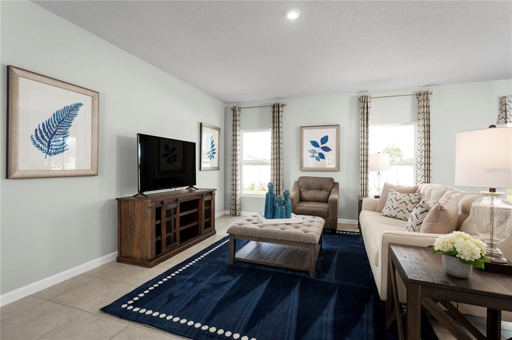 A living room features a beige sofa, a dark blue rug, and a wooden media console — 1566 STARLING SONG LANE, LAKELAND, FL