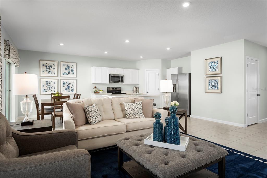 An open-concept living room and kitchen area featuring a beige sofa and tile flooring — 1566 STARLING SONG LANE, LAKELAND, FL