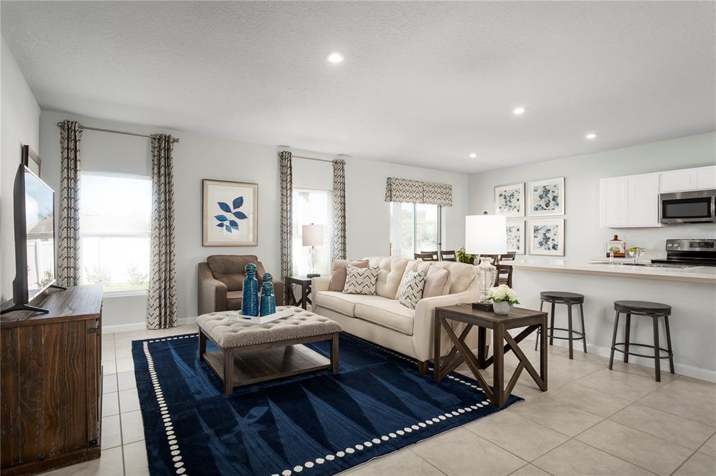 A living room features a blue area rug, beige sofa, and an open kitchen island — 1566 STARLING SONG LANE, LAKELAND, FL