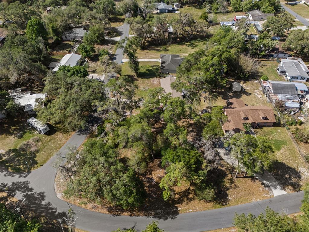An aerial view shows a wooded residential lot with a house and surrounding properties — 5043 CARDINAL DRIVE, DADE CITY, FL