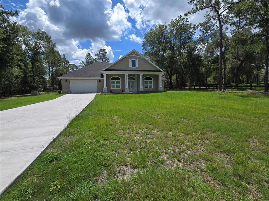 A single-story house with a beige exterior, a two-car garage, and a concrete driveway — 9855 SW 125TH TERRACE, DUNNELLON, FL