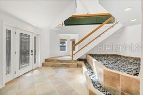 An entryway features tile flooring, a staircase with wooden railings, and a decorative rock bed — 79 TIDY ISLAND BOULEVARD UNIT 79, BRADENTON, FL