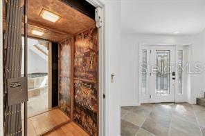 An interior view shows a residential elevator with decorative panels next to a front entryway — 79 TIDY ISLAND BOULEVARD UNIT 79, BRADENTON, FL