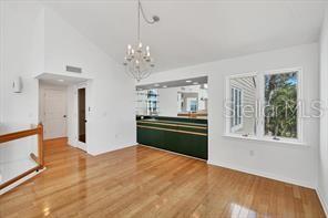 A room with hardwood floors, a vaulted ceiling, a chandelier, and a built-in wet bar — 79 TIDY ISLAND BOULEVARD UNIT 79, BRADENTON, FL