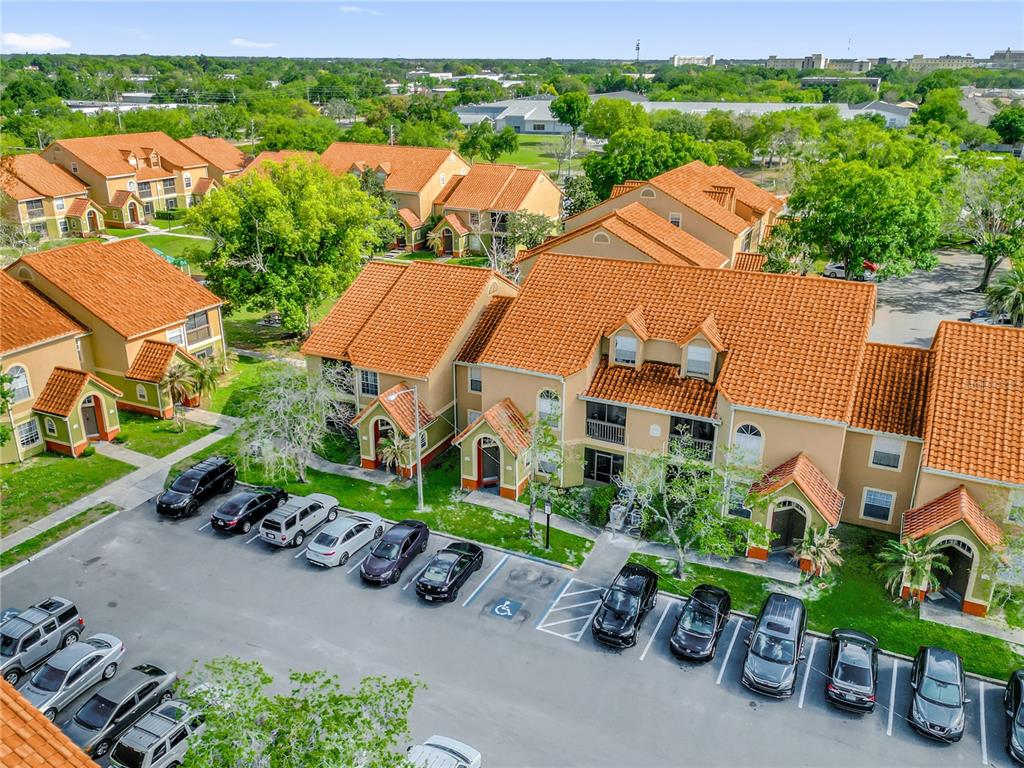 An aerial view shows multi-story apartment buildings with orange tile roofs and a parking lot — 405 FOUNTAINHEAD CIRCLE UNIT 247, KISSIMMEE, FL