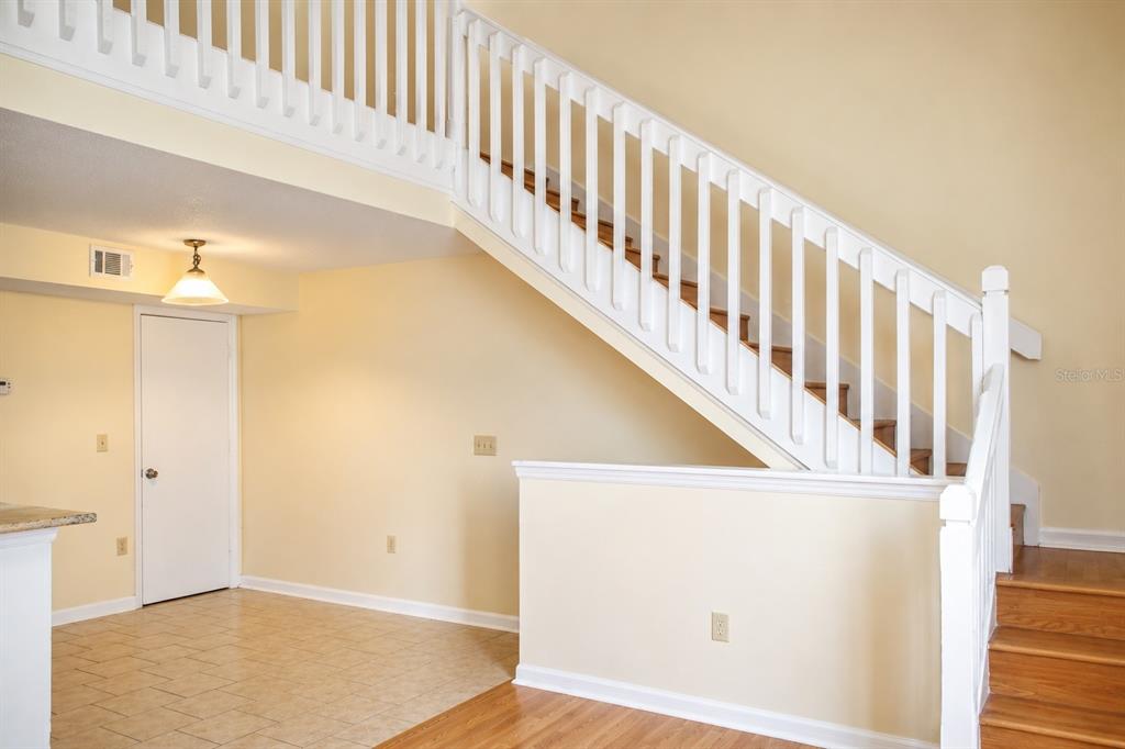 A staircase with white railings leads to an upper level above a tiled entryway — 405 FOUNTAINHEAD CIRCLE UNIT 247, KISSIMMEE, FL