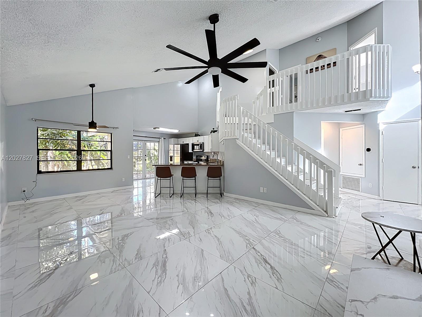 A bright, open-concept living area features white marble tile floors, a staircase, and a kitchen — OTHER CITY - IN THE STATE OF FLORIDA, FL