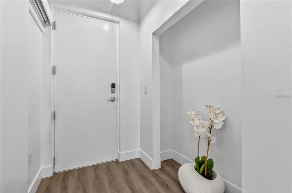 An entryway features a white door, light wood-look flooring, and a white orchid in a vase — 525 E JACKSON STREET UNIT 403, ORLANDO, FL