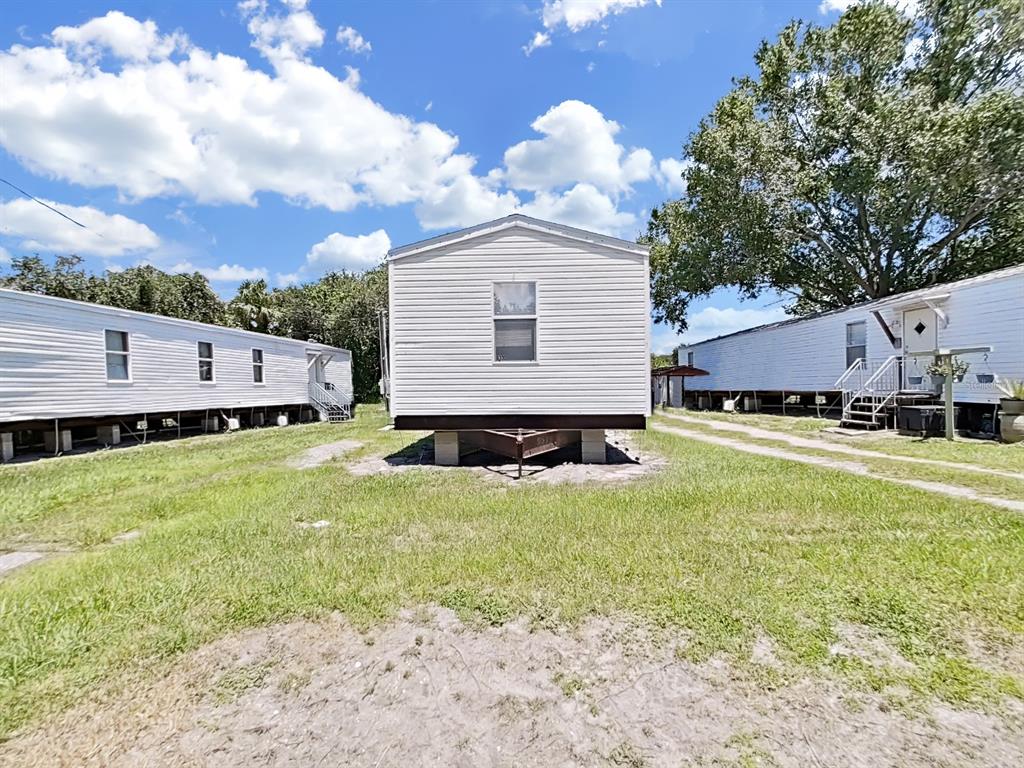 A white mobile home sits on a grassy lot between two other similar structures — 6330 EUGENE ACRES LANE, GIBSONTON, FL