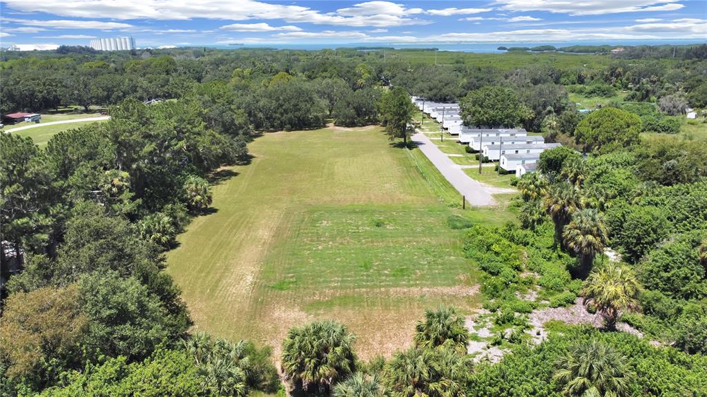 An aerial view shows a large, grassy vacant lot adjacent to a mobile home park — 6330 EUGENE ACRES LANE, GIBSONTON, FL